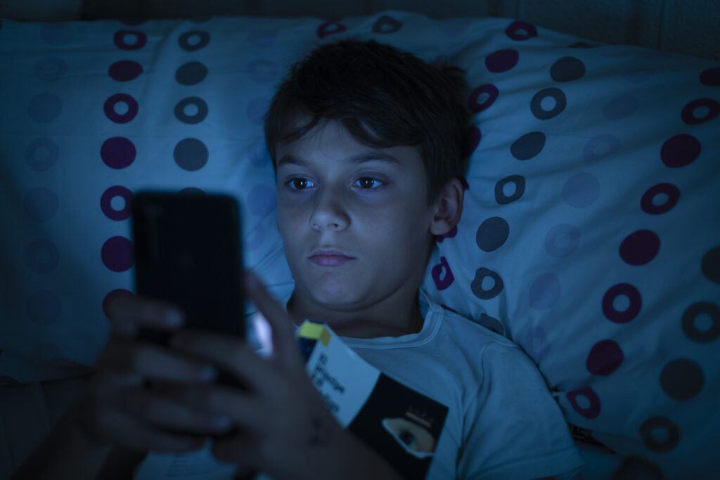 bambino che guarda il telefono a letto