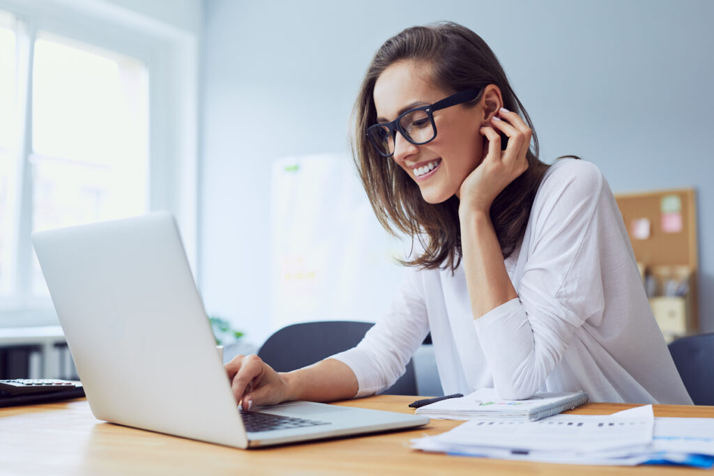 Ragazza indossa occhiali mentre lavora al computer che emana luce blu.
